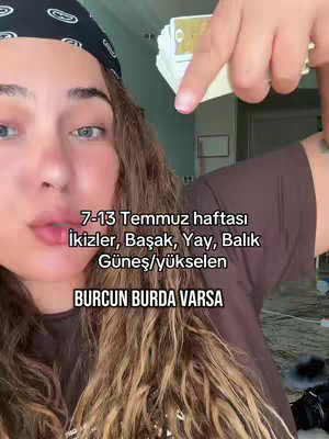 The cover image shows a woman in a close-up shot, holding a stack of what appear to be tarot cards. She's wearing a black bandana and has long, wavy brown hair. Text overlays are present:  "7-13 Temmuz haftası İkizler, Başak, Yay, Balık Güneş/yükselen" and "BURCUN BURDA VARSA". The color palette appears natural, and the composition focuses on her face and hand.