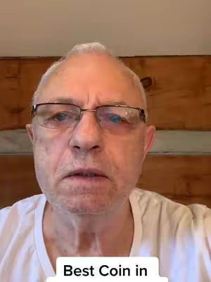 The cover image is a close-up of an older man wearing glasses, with a concerned expression. He's in front of a wooden background. A text overlay at the bottom reads: "Best Coin in".