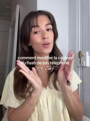 The image shows a young woman facing the camera with hands gesturing towards the sides. Above her is text in French. She wears a light-yellow top, and the background suggests an indoor setting, possibly a bedroom or a room with a mirror. The composition is evenly lit, with the text at the center.