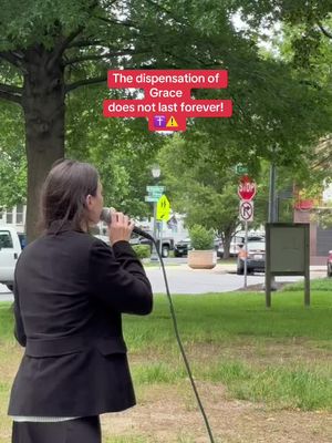 A woman wearing a black suit stands outside, speaking into a microphone. Text overlays in a red box on top of the image say 'The dispensation of Grace does not last forever!’ and includes religious symbols. The background features trees, grass, and street signs.