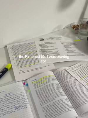 A top-down shot of a desk covered in papers, notebooks, and a highlighter. The text overlay reads 'the Pinterest life I was praying for'. The image is primarily cool-toned, with a mix of paper textures and the brightness of a highlighter.
