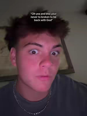 A young man with short, spiky brown hair and wide eyes stares directly at the camera. He has a slight smirk. Above him, a text overlay quotes "Oh yea and btw your never to broken to be back with God". The background is dimly lit and out of focus.