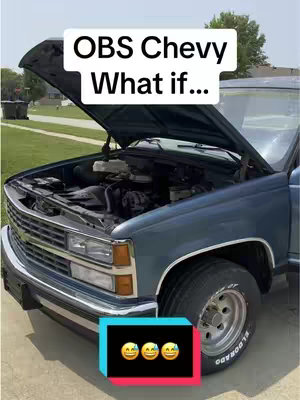A slightly angled shot of a blue Chevy truck with its hood open in natural lighting. The front of the truck is visible, including the headlights, grill, and tires. Above the truck, a rectangular text overlay reads OBS Chevy What if...