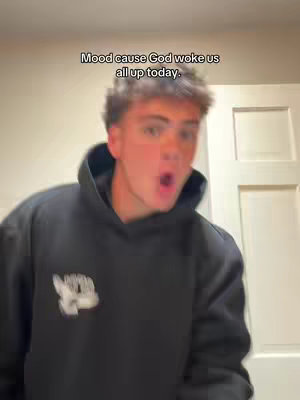 A young man is in a room, wearing a black hoodie, his mouth wide open as if he's shouting. Text overlayed on the image reads: 'Mood cause God woke us all up today.'