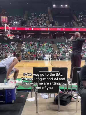 The video shows a scene from a basketball game. A player in a white jersey is on the left, preparing to play. In the background, the stands are packed with spectators. The overlay text reads, 'POV: you go to the BAL African League and VJ and Khaby Lame are sitting in front of you.'