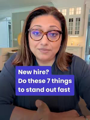 A woman with long brown hair and glasses is framed from the chest up, looking at the camera. Behind her is a bright, well-lit kitchen. Overlaid on the screen is a blue box with white text giving advice for new hires.