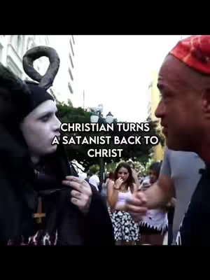 The image shows two men in conversation. One man is dressed in black and has white face paint and a black head covering with a horned ornament. The other man is speaking to him. Text overlays read, 'Christian Turns a Satanist Back to Christ.' A few other people are visible in the background.