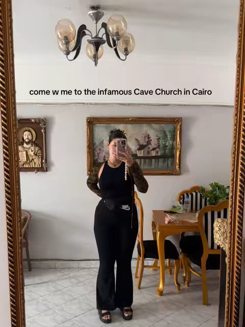 A woman stands in front of a mirror, taking a selfie. The mirror frames her, showing a room with a chandelier, artwork, and other furniture. Text overlays the image.