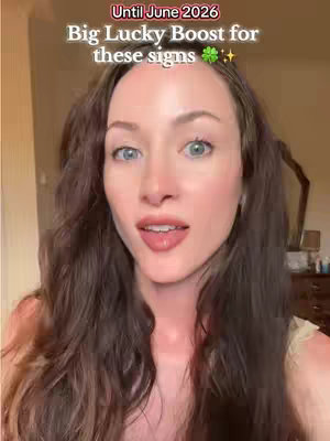 A woman with long brown wavy hair is centered in the frame, looking towards the camera with a slight smile. She has blue eyes and natural-looking makeup with pink lipstick. Above her head is a text overlay, and the background appears to be a room with a mirror and some furniture.