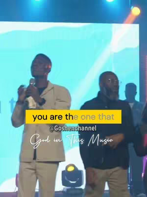 The cover image shows a live music performance with two men on a stage. The background is a blurred image with a blue hue that creates a vibrant stage presence. The man on the left is holding a microphone, dressed in a light tan suit jacket and light pants. The other man is to the right, wearing glasses and a black jacket. Text overlays read 'you are the one that', '@Goshenchannel' and 'God in This Music'.