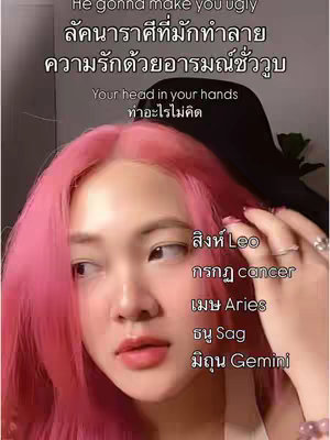 A selfie-style vertical image features a young woman with bright pink hair and a thoughtful expression, looking slightly off-center. The image is dominated by her face and upper torso. Overlay text at the top includes both English and Thai characters, while text on the right lists astrological signs. The background is blurred, focusing attention on the woman. The overall composition is straightforward, with a soft aesthetic enhanced by the bright hair color.