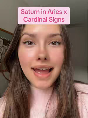 A selfie-style shot with a young woman centered, facing the camera with a slight smile and open mouth. A pink rectangular overlay is placed above her head. The background is out of focus, suggesting an interior setting.