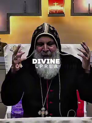 A medium shot captures an older man in religious attire, seated and gesturing with both hands. The man has a full white beard and is wearing a black robe under a black and gold hooded garment. A large pendant cross hangs around his neck. The background is light brown. Overlayed on the man are the white text 'DIVINE' and 'LPRAY'. Overall the video has a religious theme.