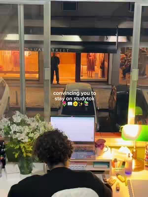 The image shows a person working on a laptop at a desk adorned with flowers, in front of the glass facade of a business. The text overlay says 'convincing you to stay on studytok.'