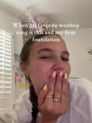 A close-up shot of a young woman partially covering her mouth with her hand. She is wearing a white shirt and has her hair pulled back. Text overlayed on the image reads "When his favorite worship song is this and not firm foundation".