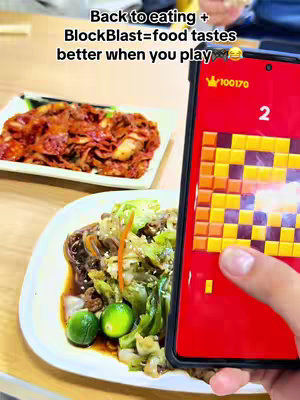 The cover image shows a person holding a phone displaying a game. The phone screen shows a level from BlockBlast. The background has a blurred view of a table with various dishes.