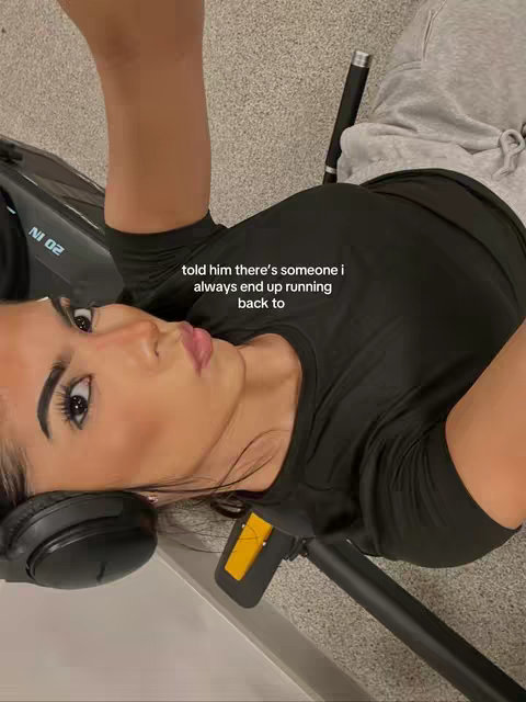A woman is lying down, looking towards the camera. She is wearing black athletic wear and has headphones on. Text overlayed on the image says, "told him there's someone i always end up running back to."