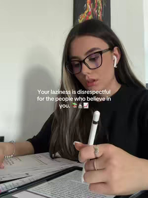A young woman with long hair and glasses is seated at a desk, holding a stylus over a tablet, with a caption layered on top.