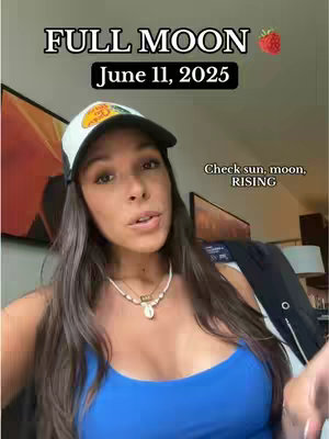 A woman with long brown hair wearing a baseball cap and blue top, facing the camera. Above her head is the text "FULL MOON June 11, 2025," and a strawberry icon. Text below says, "Check sun, moon, RISING."