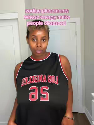 A person, with dark short hair and a black jersey is standing in front of a white door. Text overlaid in top is about zodiac signs.