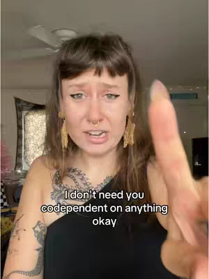 A woman with brown hair, a nose ring, and elaborate earrings points a finger at the viewer while speaking. Text is overlaid on the image.