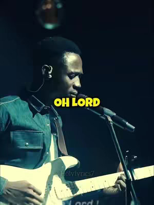 A man is playing a guitar on a stage, with a microphone in front of him. The background is dark and a text overlay says 'OH LORD'