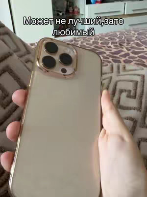 A hand holding the back of a gold iPhone, with the camera bump visible, in front of a patterned brown and beige background. Text in white on the top says, 'Maybe not the best, but favorite'.