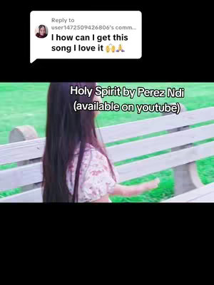 A woman with long dark hair is seen from behind, seated on a wooden bench in a park-like setting. The image is soft and has a natural light. Text overlays the image to give context and name the song available for streaming.