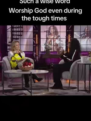 The cover image presents a scene from a talk show. Two women are seated in armchairs on a stage. The woman on the left is wearing a white blazer with a yellow and black design, while the woman on the right is in a black top with white stripes. Behind them, a large screen displays a singing performance. The background includes a decorative element with a staircase.