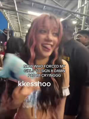 A woman with pink-streaked hair smiles widely and sticks her tongue out. Text overlays on the screen.