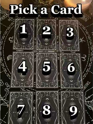 The image showcases nine tarot cards arranged in a grid on a dark surface, likely a table or cloth with astrological symbols. The cards are black with white ornate designs and the numbers 1 through 9 are written in white on each card. Above the cards, the text "Pick a Card" is displayed in a bold, stylized white font.