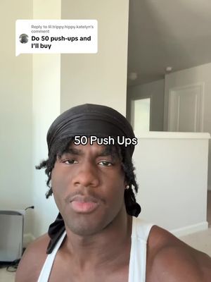 A selfie-style shot of a young man with dark hair and a black headscarf. The top portion of a speech bubble with text is shown. The man is looking at the camera. "50 Push Ups" is written underneath him. In the background is a light-colored wall and a white door.