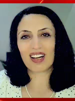 The image features a woman with black hair and a white polka-dotted top. She's looking at the camera with an open mouth, suggesting she's speaking. The background appears to be a light-colored wall, and there is a red bar at the top of the image.