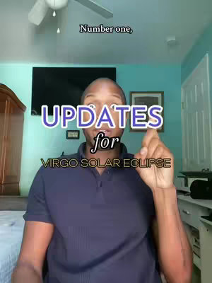 A man is positioned in front of a camera, framed from the chest up. He is wearing a navy blue polo shirt and is gesturing upwards with his right index finger. Behind him is a domestic setting with a large flat-screen TV, artwork, and blue walls. Text overlays include "Number one," and colored text stating "UPDATES for VIRGO SOLAR ECLIPSE".