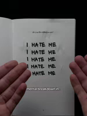 The image shows an open notebook with handwritten text and a person's hands on each side of the book. The text reads "I HATE ME" repeated multiple times. Overlay text is present at the bottom, and the overall composition has a raw, emotional feel.