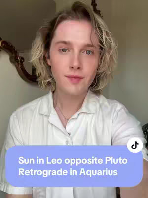 A young man with light blond, wavy hair and fair skin poses for the camera. He wears a white, button-down shirt and a simple necklace. A large, light blue shape with rounded corners overlays the bottom of the image, carrying white text. A blurred mirror and a neutral wall make up the background.