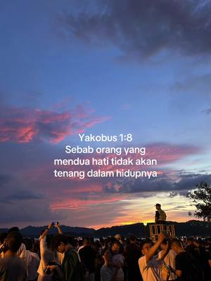 A vibrant sunset backdrop of orange, pink, and blue hues. Text overlayed on the sky quotes a bible verse with a crowd of people at the bottom.