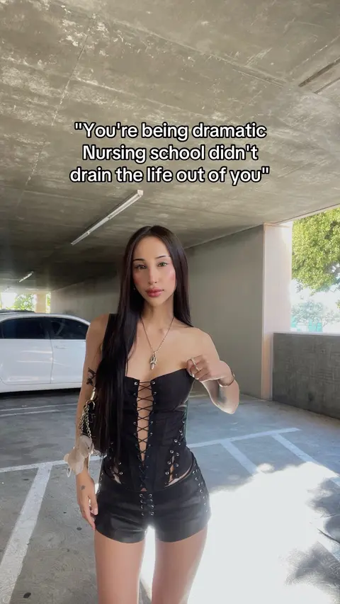 A woman poses dramatically in a parking garage, wearing a black corset and shorts. Text overlays the image.