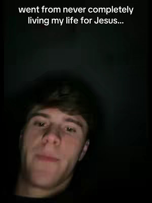 A selfie with the upper body of a young man filling most of the frame. The background is dark. The man is looking up slightly at the camera with a slight smile.