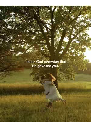 A couple embracing in a grassy field with a large tree in the background. Text overlay reads, "i thank God everyday that He gave me you."