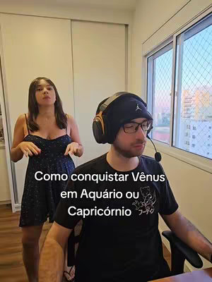 A cover image showing a man sitting at a desk with headphones, and a woman standing behind him. Text overlayed on the image reads, "Como conquistar Vênus em Aquário ou Capricórnio"