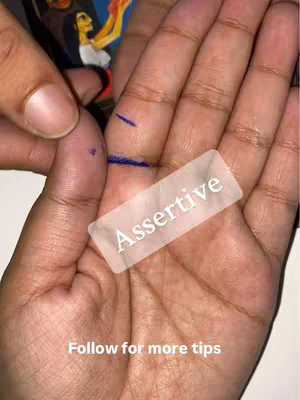 A close-up shot of a hand with a palm open and visible lines, and a clear overlay with the word "Assertive". The fingers are slightly spread, focusing on the palm and the lines drawn on the image, and a second hand is partially visible. The image is in neutral tones with the overlay adding bright elements.