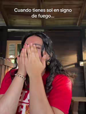 The cover image features a woman with dark hair, wearing a red shirt and obscured by her hands in front of her face. The backdrop is a combination of wooden structures, providing a rustic, outdoor setting. Text overlay at the top reads in spanish.