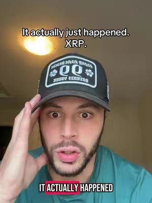 A selfie-style shot featuring a man with a hat, face close-up. The background is a bit blurry with a ceiling light. The man makes a surprised expression, touching his head.