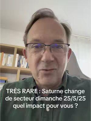 A man with glasses is centered in the frame, with overlaid text at the bottom. The background includes a bookshelf to the left and a wall. The man is wearing a green shirt and looking towards the camera.