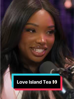A close-up shot of a Black woman with long, dark hair and makeup smiling broadly. She's facing slightly to the side, with a microphone in front of her, and a colorful lower visual overlay.