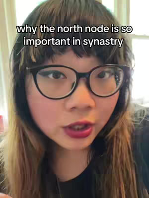 A close-up shot of a woman with dark rimmed glasses. She has dark hair with bangs, and is wearing a black top. Text overlayed onto the image reads, "why the north node is so important in synastry."