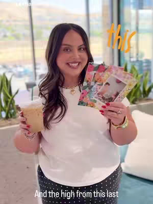The cover image shows a woman holding a cup of iced coffee in her left hand and photo prints in her right hand. She is smiling at the camera. Text overlays on the cover. The background is a bright indoor space, possibly a cafe.