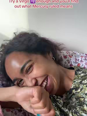 A person with dark, curly hair smiles in the image. The person is lying down in a bed, with a patterned pillow visible behind them. The person is laughing, holding their fist up to their face in an effort to contain their open mouth. The person is wearing a short-sleeved, patterned shirt, and a portion of a green shirt is visible. Text is overlaid on top of the image.