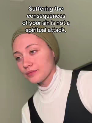 A woman with light skin and dark hair wears a white turtleneck and a black sleeveless top. She has a light olive headscarf. The background has a wall with a grey color. White text is overlaid at the top, with an emotional expression.